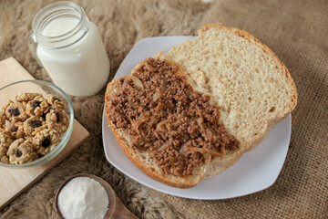 Bread with minced beef and union on a table. With white milk and snack for breakfast	
