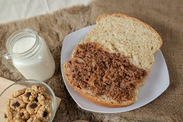Bread with minced beef and union on a table. With white milk and snack for breakfast	
