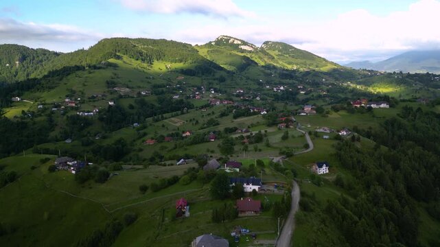 High angle flyover footage over the magnificent picturesque village of Magura in Brasov region of the Romanian Carpati mountains. Drone shot of the gem of romanian tourism on a green summer day.
