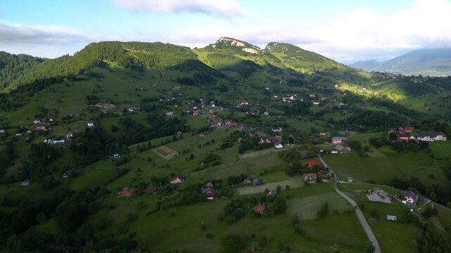 High angle flyover footage over the magnificent picturesque village of Magura in Brasov region of the Romanian Carpati mountains. Drone shot of the gem of romanian tourism on a green summer day.
