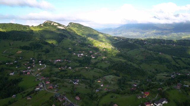 High angle flyover footage over the magnificent picturesque village of Magura in Brasov region of the Romanian Carpati mountains. Drone shot of the gem of romanian tourism on a green summer day.
