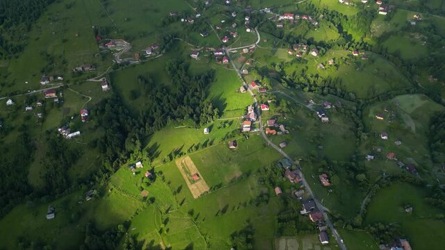 High angle flyover footage over the magnificent picturesque village of Magura in Brasov region of the Romanian Carpati mountains. Drone shot of the gem of romanian tourism on a green summer day.
