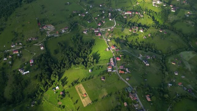 High angle flyover footage over the magnificent picturesque village of Magura in Brasov region of the Romanian Carpati mountains. Drone shot of the gem of romanian tourism on a green summer day.
