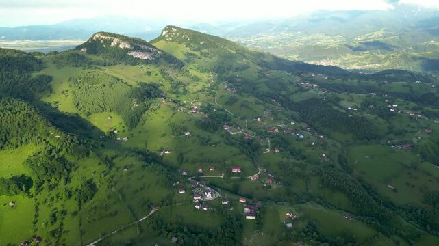 High angle flyover footage over the magnificent picturesque village of Magura in Brasov region of the Romanian Carpati mountains. Drone shot of the gem of romanian tourism on a green summer day.
