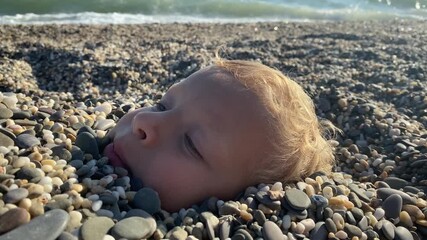 Children playing on the beach. Happy child face buried in sand close-up. Children summer vacation. Yevpatoriya, Crimea, Russia 2024