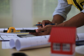 Fototapeta premium Asian architect and designer using blueprints and laptop to draw building structure in office. Construction concept, Engineering concept, Building plan, Building permit, Home architecture, Engineering