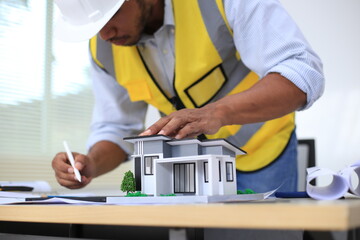 Asian architect and designer using blueprints and laptop to draw building structure in office. Construction concept, Engineering concept, Building plan, Building permit, Home architecture, Engineering