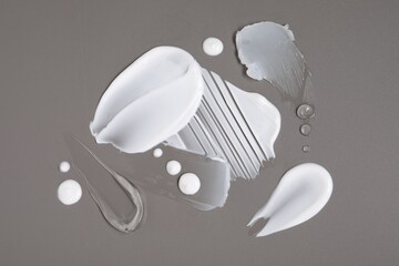 Face cream and gel on grey background, top view
