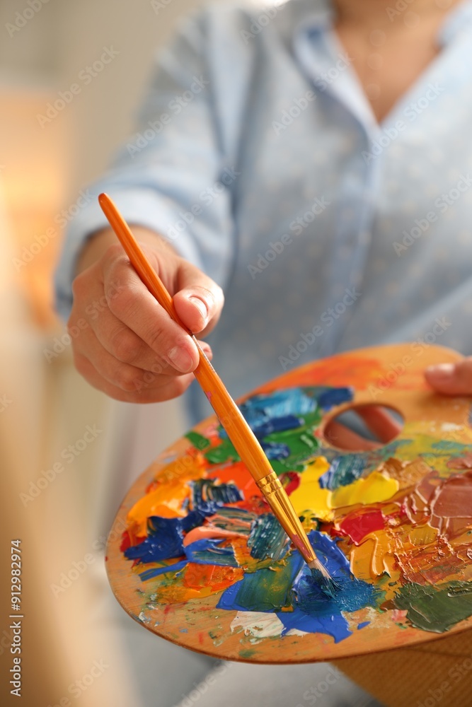 Wall mural Woman mixing paints on palette with brush indoors, closeup