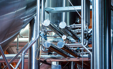 Intricate network of stainless steel pipes and gauges at craft brewery, complex engineering behind beer production.