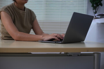 Fototapeta premium Successful Asian businesswoman sitting at desk working using laptop computer in office. Business and people concept. Businesswoman using laptop computer and working with documents.