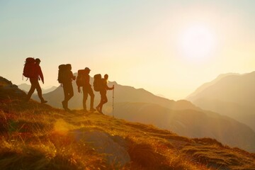 A group of four people are hiking up a mountain. The sun is setting in the background, casting a warm glow over the landscape. The hikers are carrying backpacks and are walking in a line