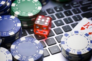 A keyboard with a red die and a deck of cards on top of it. Concept of excitement and anticipation for a game of poker