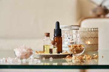 Several bottles of aromatherapy essential oil with pink Himalayan sea salt, dry herbs and candles in a living room