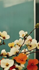 Blossoms in various shades bloom against a textured teal wall