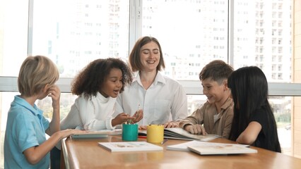 Happy diverse student and smart teacher drawing and coloring by using marker at drawing book. Multicultural smart learner using drawing book while talking to skilled caucasian instructor. Erudition.