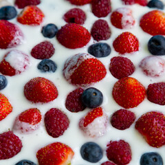 In a plate with whipped cream ripe berries strawberries raspberries and blueberries on a light background