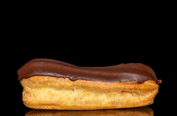 One eclair with cream, macro, isolated on black background.