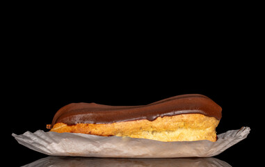 One eclair with cream, macro, isolated on black background.