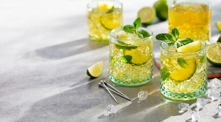 Mojito cocktail with lime and mint, lemonade, ice tea in glasses and jug. Grey background. Copy space.