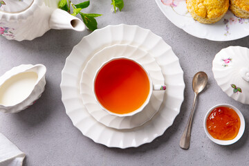 Cup of tea with scones with jam, clotted cream. Gray background. Top view.