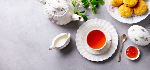 Cup of tea with scones with jam, clotted cream. Grey background. Copy space. Top view.