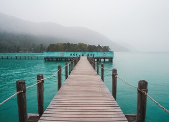 Naklejka premium A Beautiful Serene Lake View Featuring a Wooden Pier Set Within a Misty Landscape Scene