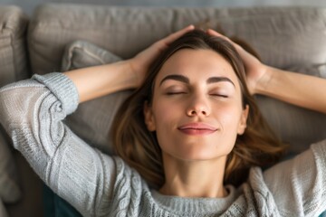 Fototapeta premium A woman is laying on a couch with her head on her hand. She is smiling and she is relaxed