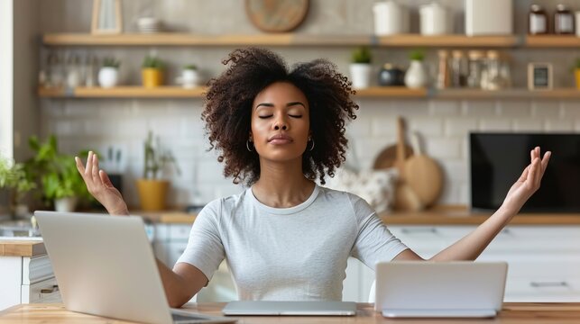 Woman meditating with two laptops in bright kitchen