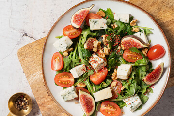 salad with figs, rucola and walnuts. salad with rucola. salad on a light background. salad with blue cheese.
