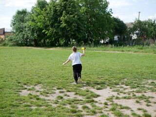 A young girl happily running with a toy water gun on a sunny summer day