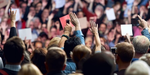 Fototapeta premium A crowd of people are holding up signs and waving their hands in the air. Scene is energetic and enthusiastic