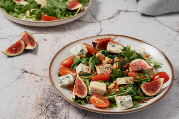 salad with figs, rucola and walnuts. salad with rucola. salad on a light background. salad with blue cheese.

