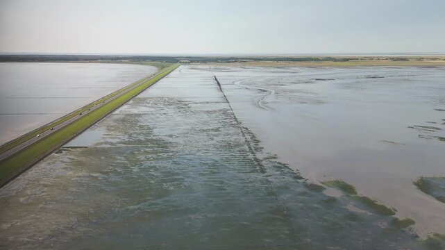 Aerial video of the mudflats divided by the green road leading to Romo Island, Denmark.