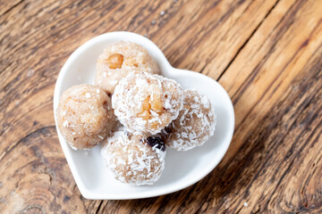 Close up Laddu from semolina Indian sweets on a white plate. Coconut Bliss Balls on Heart-Shaped Dish