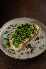 a sandwich with green onions and green peas lies on a light plate