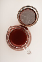 Cherry nectar in a jug and a glass on a white background.