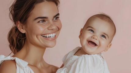 A mother and her delighted baby share a warm moment in a light studio environment.