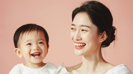 Studio image of an Asian mother and her beaming baby, showcasing their affectionate bond and mutual smiles.