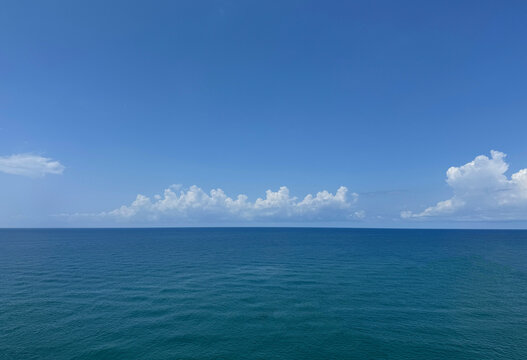 Blue sea calm water and white clouds in the sky.