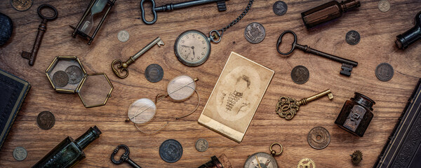 A collection of antique antiques is spread out on the table. Old coins, glasses, photography, glass bottles, keys, watch and compass. Vintage collection. History  background. - Powered by Adobe