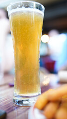 A glass of beer is on a table next to a plate of french fries