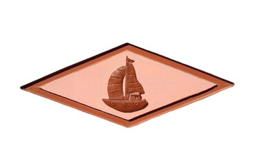 Photo of a sailboat, elegantly carved on a brown-pink wall in the shape of a rhombus, isolated on white background.