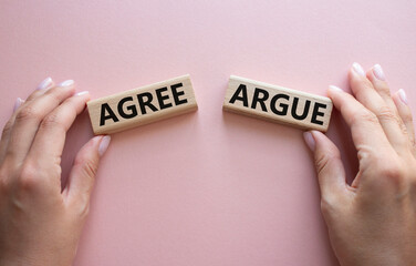 Agree or Argue symbol. Concept word Agree or Argue on wooden blocks. Businessman hand. Beautiful pink background. Gender and Agree or Argue concept. Copy space