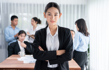 Portrait of happy young asian businesswoman looking at camera with motion blur background of business people movement in dynamic business meeting. Habiliment