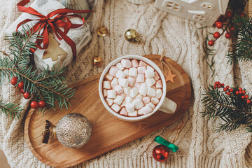 Christmas background. Cup of hot chocolate with marshmallows, christmas ornaments and gift, cozy knitted sweater and fir branches flat lay. Merry Christmas. Winter hygge