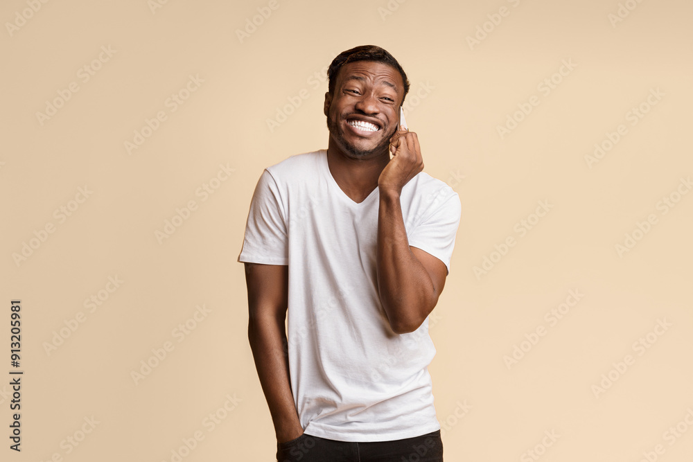 Poster afro guy laughing talking on cellphone standing over yellow studio background. empty space for text