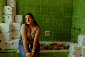 Mujer latina sentada en una tina de baño con pelotas de colores