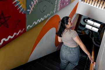 Mujer latina bajando las escales y la pared de colores
