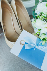 Accessories of the bride. Wedding shoes for the bride. White high-heeled shoes near wedding rings, wedding jewelry.